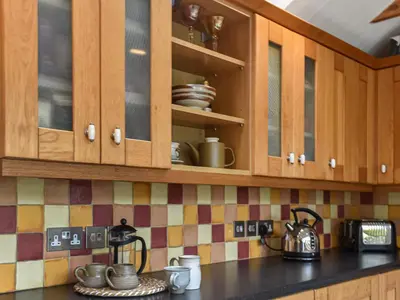 a kitchen with wooden cabinets and utensils at Gew Cottage in Helston