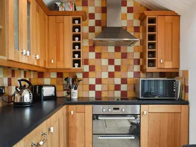 a kitchen with a stove and a microwave at Gew Cottage in Helston