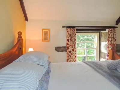a bedroom with a bed and a window at Gew Cottage in Helston