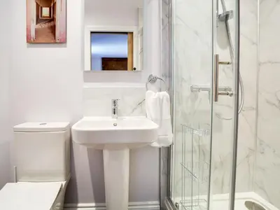 a white bathroom with a sink and a shower at Tower Hill in Bodmin