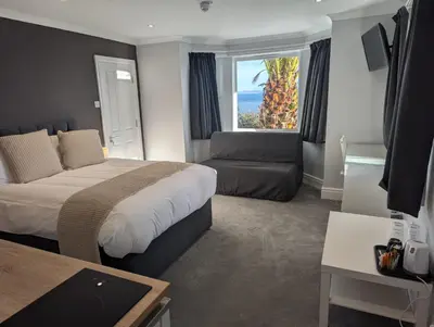 a hotel room with a bed and a couch and a window at Fieldhead Hotel, Looe in Looe