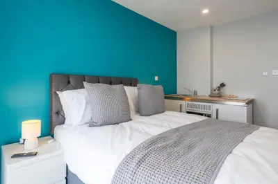 a bedroom with a large white bed with a blue wall at Fieldhead Hotel, Looe in Looe