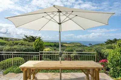a white umbrella sitting on a wooden table at Peaceful Home Sea Views Private Parking in Treknow