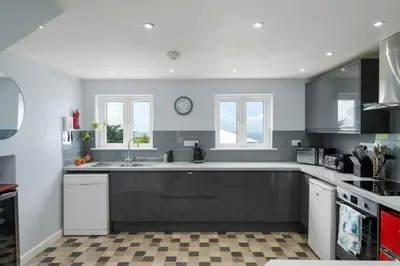 a kitchen with a sink and a clock on the wall at Peaceful Home Sea Views Private Parking in Treknow