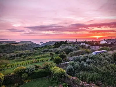 a sunset over a garden with the sun setting in the background at Peaceful Home Sea Views Private Parking in Treknow