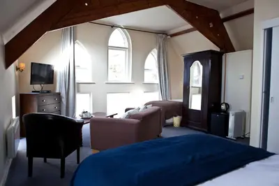 a bedroom with a bed and a couch and windows at The Old School Hotel in Port Isaac