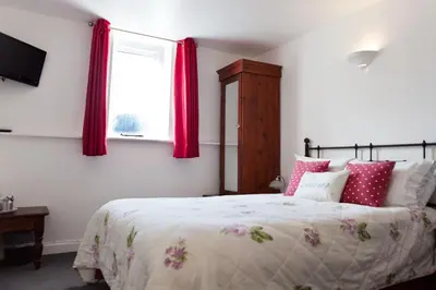 a bedroom with a bed with red curtains and a window at The Old School Hotel in Port Isaac