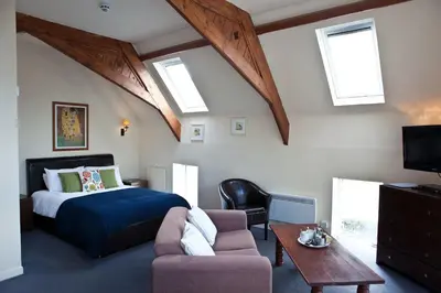 a bedroom with a bed and a couch and windows at The Old School Hotel in Port Isaac