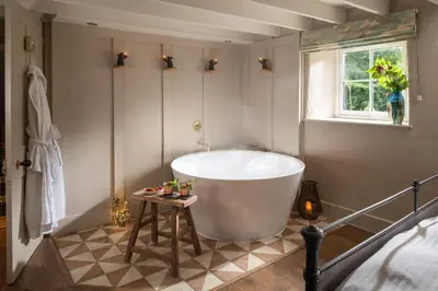 a large bath tub in a bathroom with a window at Topsy Turvy and Hillside Spa at Tregoose Old Mill in Newquay