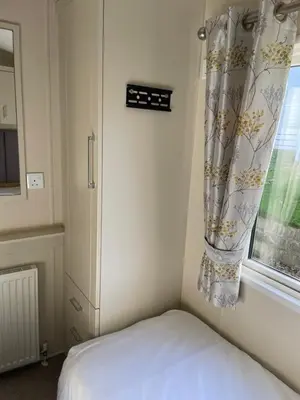a bedroom with a bed with a curtain and a window at Rubys Retreat - 6 Berth Caravan in Newquay, Cornwall in Newquay