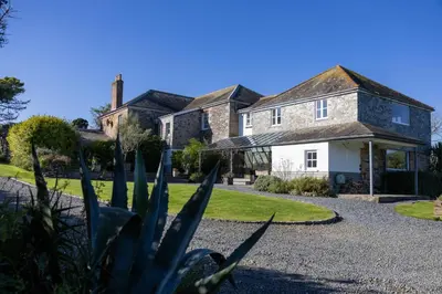 a house with a gravel driveway in front of it at Trevornick Farm House in Newquay