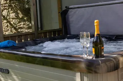 a bottle of champagne and glasses in a hot tub at Trevornick Farm House in Newquay