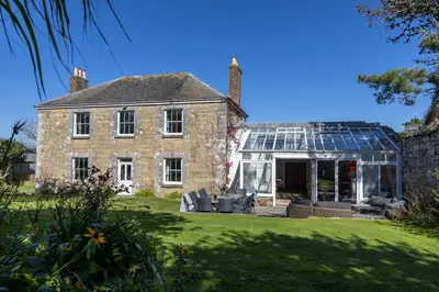 an old stone house with a glass greenhouse at Trevornick Farm House in Newquay