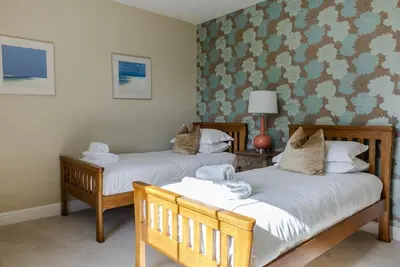 two beds in a room with green wallpaper at Trevornick Farm House in Newquay