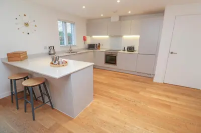 a kitchen with white cabinets and a wooden floor at Una, Lodge 73 in St Ives