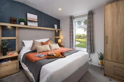 a bedroom with a large bed and a window at Hot Tub Lodge Cornwall in St Austell