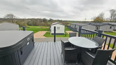 a patio with a table and chairs on a deck at Hot Tub Lodge Cornwall in St Austell