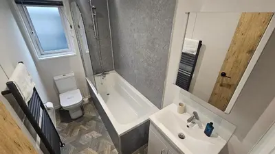 a bathroom with a tub and a toilet and a sink at Hot Tub Lodge Cornwall in St Austell