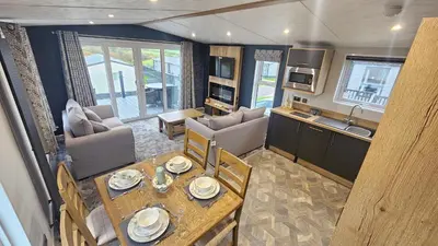 a kitchen and living room with a table and chairs at Hot Tub Lodge Cornwall in St Austell