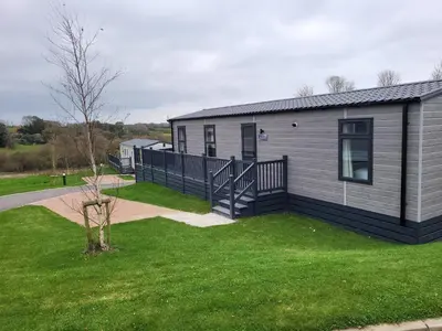 a mobile home with a deck and a yard at Hot Tub Lodge Cornwall in St Austell