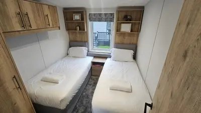 two beds in a small room with a window at Hot Tub Lodge Cornwall in St Austell