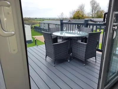 a patio with a table and chairs on a deck at Hot Tub Lodge Cornwall in St Austell
