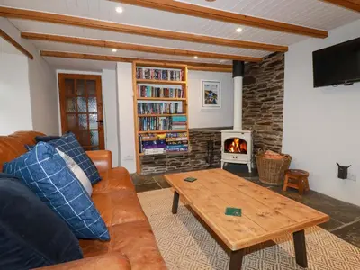 a living room with a couch and a wood stove at Crab Cottage in Delabole