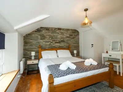 a bedroom with a large bed with a brick wall at Crab Cottage in Delabole