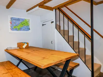 a wooden table in a room with a staircase at Crab Cottage in Delabole