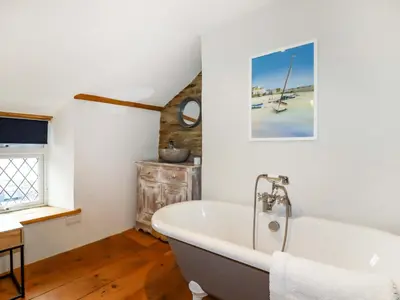 a white bath tub in a bathroom with wooden floors at Crab Cottage in Delabole