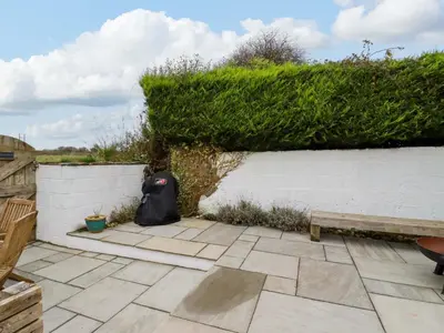 a garden with a bench and a hedge at Crab Cottage in Delabole