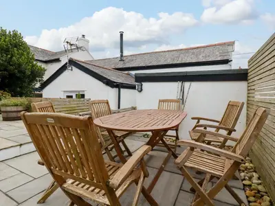 a wooden table and chairs on a patio at Crab Cottage in Delabole