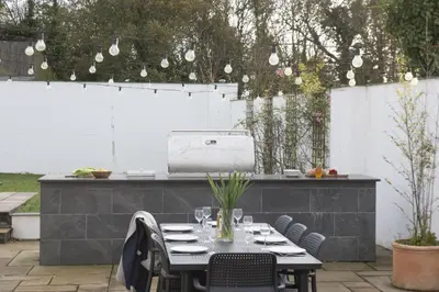 a patio with a table and chairs and a grill at Trebyre in Padstow