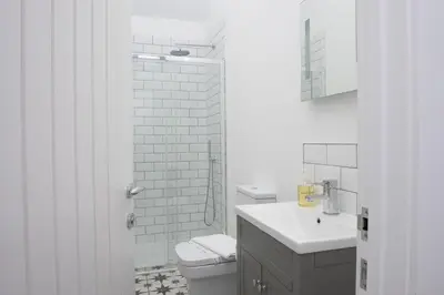 a white bathroom with a toilet and a sink at Trebyre in Padstow