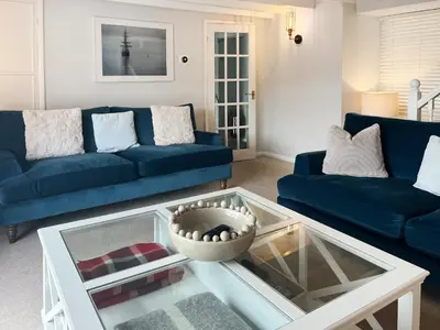 a living room with a blue couch and a glass table at Crew Quarters in Fowey
