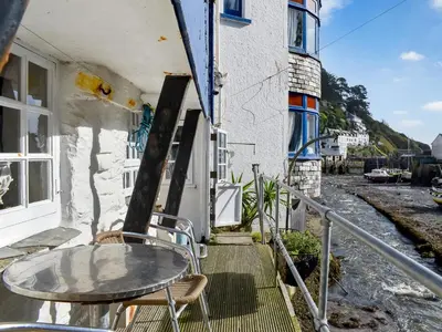 a table and chairs on a balcony of a building at Harbour Studio in Polperro