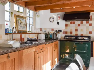 a kitchen with wooden cabinets and a green oven at Harbour Studio in Polperro