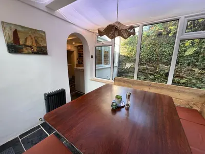 a large wooden table in a room with windows at Rosebank Cottage in Boscastle