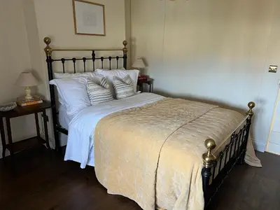 a bedroom with a large bed with white sheets and pillows at Rosebank Cottage in Boscastle