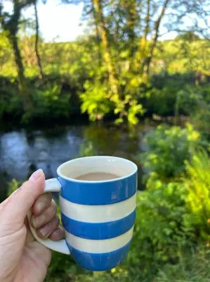 a person holding a blue and white cup of coffee at The Artists Studio in Saint Cleer