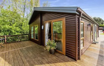 a wooden cabin with a deck with a patio at Cousins beach house Three bedroom lodge St Minver in Wadebridge