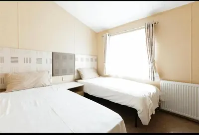 two beds in a room with a window at Cousins beach house Three bedroom lodge St Minver in Wadebridge