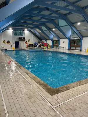 a large swimming pool with blue water in a building at Cousins beach house Three bedroom lodge St Minver in Wadebridge