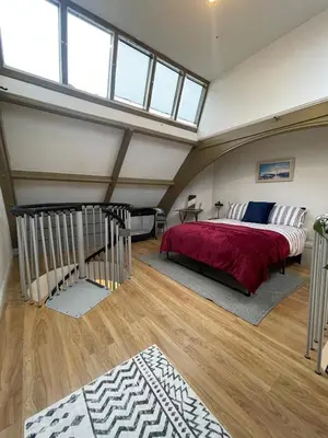 a bedroom with a bed in a room with windows at The Loft St Austell in St Austell