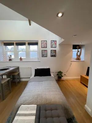 a bedroom with a bed and a desk and windows at The Loft St Austell in St Austell
