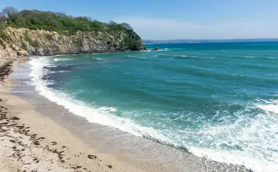 a sandy beach with a boat in the ocean at The Loft St Austell in St Austell
