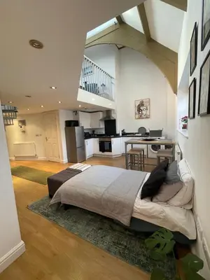 a bedroom with a large bed and a kitchen at The Loft St Austell in St Austell