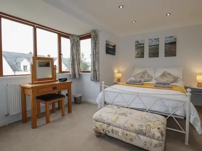 a bedroom with a bed and a desk and windows at 3 The Bowling Green in Truro