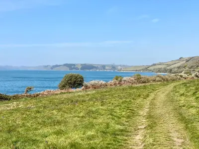 a dirt road next to the ocean on a hill at 3 The Bowling Green in Truro