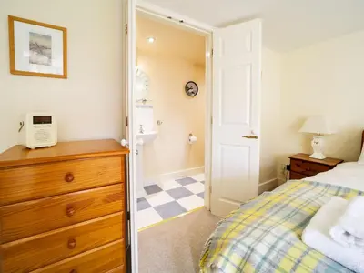 a bedroom with a bed and a dresser and a bathroom at Dolphin Cottage in Charlestown
